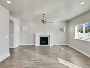 Unfurnished living room featuring light wood-style flooring, recessed lighting, a fireplace, plenty of natural light, and a textured ceiling