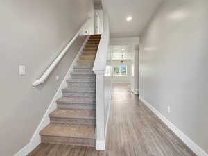Stairway with wood finished floors and recessed lighting