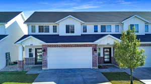 View of front of property with a shingled roof, brick siding, board and batten siding, and concrete driveway
