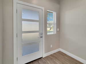 Doorway with baseboards and wood finished floors