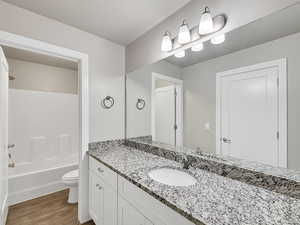 Bathroom with vanity, dark wood-style floors, tub / shower combination, and a textured ceiling