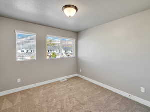 Empty room with a textured ceiling and light colored carpet