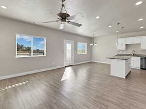 Kitchen featuring white cabinets, a textured ceiling, open floor plan, recessed lighting, and light wood-style flooring