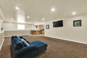 Living area with a textured ceiling, recessed lighting, light carpet, and bar area