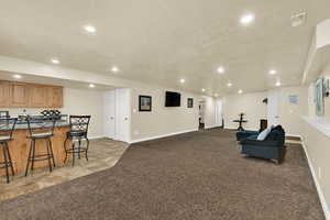 Living area with recessed lighting, a textured ceiling, light colored carpet, and light tile patterned floors