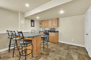 Kitchen with dark countertops, open shelves, a breakfast bar, a textured ceiling, and recessed lighting