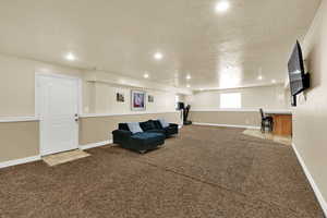 Living area featuring dark carpet, recessed lighting, and a textured ceiling