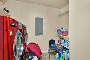 Laundry room featuring tile patterned floors, electric panel, and washer and dryer
