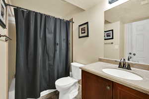 Full bath with a textured ceiling, vanity, shower / bath combo, and light tile patterned flooring