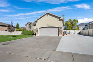 View of front of house with stone siding, concrete driveway, stucco siding, and a garage