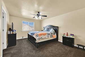 Bedroom with dark colored carpet, a textured ceiling, and ceiling fan