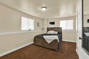 Bedroom with dark colored carpet and a textured ceiling