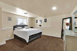 Bedroom with a textured ceiling and dark colored carpet
