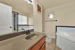 Bathroom featuring light tile patterned floors, vanity, a bath, and a shower stall