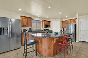 Kitchen featuring a breakfast bar area, stainless steel appliances, brown cabinets, and recessed lighting
