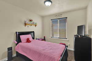 Bedroom with dark carpet and a textured ceiling