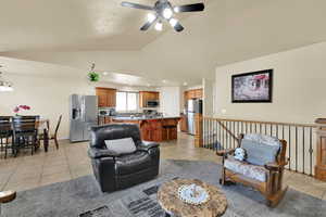 Living area with light tile patterned floors, vaulted ceiling, a ceiling fan, recessed lighting, and a chandelier