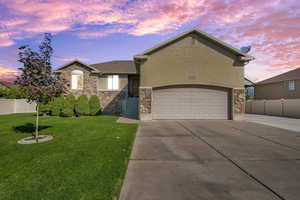 View of front of property with stone siding, driveway, and stucco siding