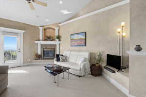 Carpeted living room with a high end fireplace, vaulted ceiling, ceiling fan, and recessed lighting