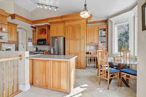 Kitchen featuring vaulted ceiling, light countertops, open shelves, appliances with stainless steel finishes, and a peninsula