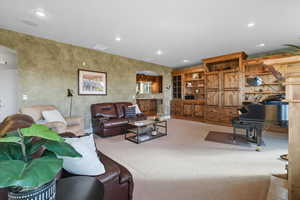 Living room featuring arched walkways, recessed lighting, and light carpet