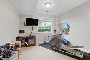 Exercise room featuring light carpet and baseboards