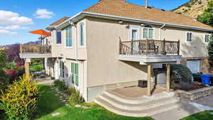 Rear view of property with stucco siding, stone siding, a mountain view, and a balcony