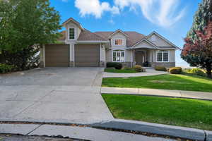 View of front facade featuring stucco siding, stone siding, a front lawn, and driveway