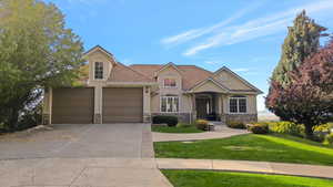 View of front of property with a front yard, stucco siding, concrete driveway, and stone siding