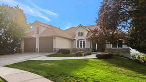 View of front of home featuring a front lawn, stone siding, stucco siding, concrete driveway, and an attached garage