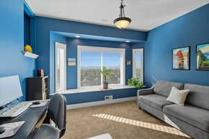 Home office with carpet floors and healthy amount of natural light