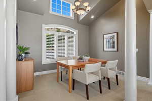 Dining room featuring decorative columns, light carpet, a towering ceiling, and recessed lighting