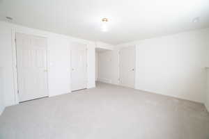 Unfurnished bedroom featuring light carpet and baseboards