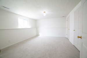 Empty room with a textured ceiling and carpet flooring