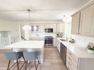 Kitchen with stainless steel appliances, decorative backsplash, pendant lighting, and a breakfast bar
