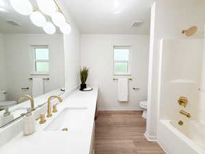Bathroom with vanity, tub / shower combination, and light wood-style flooring