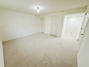 Unfurnished bedroom featuring light colored carpet and two closets