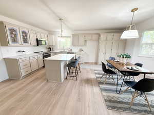 Kitchen featuring pendant lighting, a kitchen bar, a kitchen island, tasteful backsplash, and appliances with stainless steel finishes