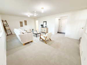 Living room featuring light carpet and a ceiling fan