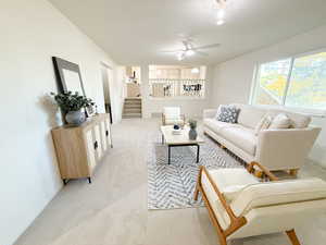 Carpeted living area featuring stairway and a ceiling fan