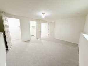 Unfurnished bedroom with light colored carpet, a spacious closet, and a textured ceiling