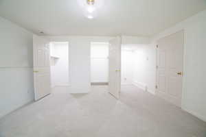 Unfurnished bedroom with light colored carpet and a walk in closet