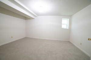 Carpeted spare room featuring a textured ceiling