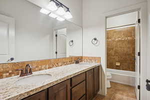 Guest Full bath featuring double vanity, shower / bathtub combination, and tasteful backsplash