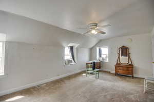 Living area with lofted ceiling, carpet floors, healthy amount of natural light, and ceiling fan