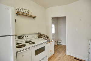 Kitchen with white appliances, white cabinetry, light wood-type flooring, open shelves, and light countertops
