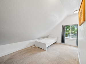 Bedroom with carpet floors, lofted ceiling, and a textured ceiling