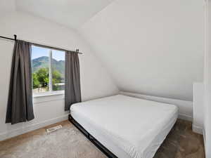 Carpeted bedroom featuring lofted ceiling and a mountain view