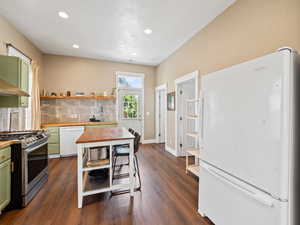 Kitchen featuring white appliances, tasteful backsplash, open shelves, green cabinetry, and butcher block countertops