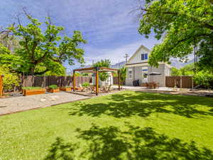 Fenced backyard featuring a patio area, a vegetable garden, an outdoor structure, and a gazebo